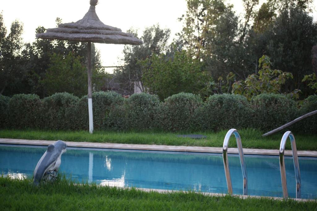 Piscine avec parasol en paille au crépuscule, Bougainvilla Retreat